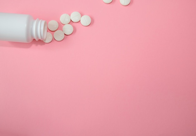 White pills next to white jar isolated on the pink horizontal banner copy space medical concept