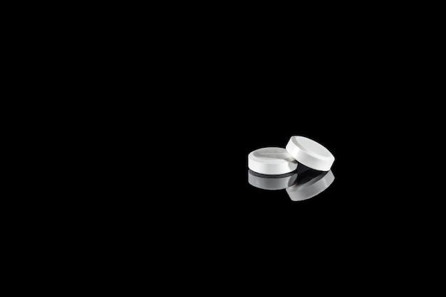 White pills with reflection isolated on black