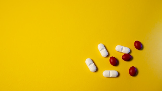 White pills on a yellow background with one red and white capsule on the left.