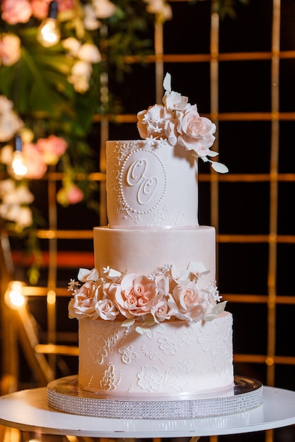 White-pink beautiful wedding cake on the background of the evening wedding arch.