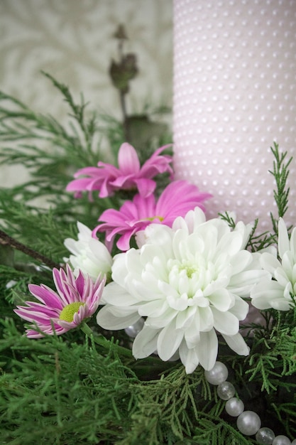 White and pink chrysanthemums with ivy and juniper branches. Festive flower arrangement.Chrysanthemums and candle