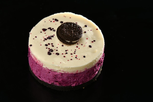 A white and pink dessert with a black circle on the top.