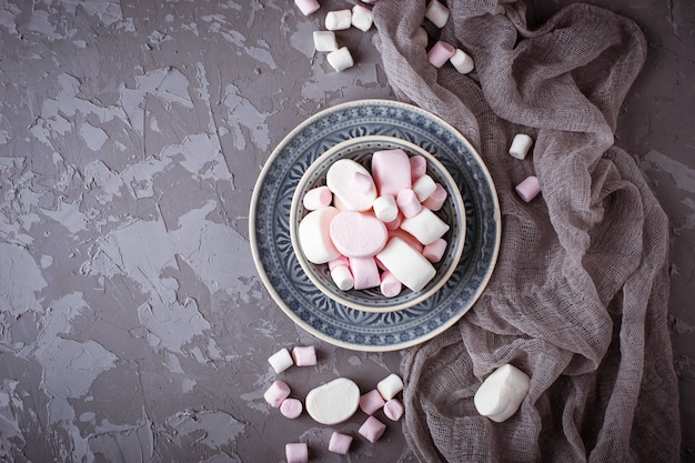 White and pink marshmallows on gray concrete background. Selective focus