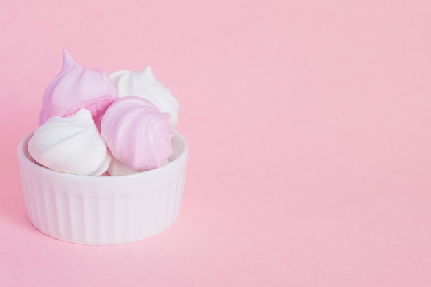 White and pink twisted meringues in porcelain bowl on pink