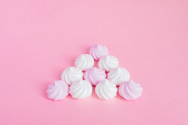 White and pink twisted meringues in a shape of pyramid on pink background, greeting card, copy space