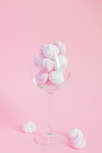 White and pink twisted meringues in  a vine glass on pink background