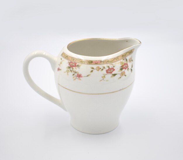 Photo a white pitcher with a floral design and a gold rim.