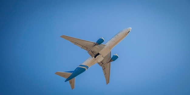 White plane flies in the sky Bottom view Takeoff and landing Arrival and departure Passenger plane isolated on blue background Airplane flying Travel by air transport Copy space