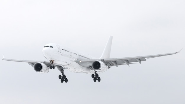 White plane with chassis in the sky preparing for landing