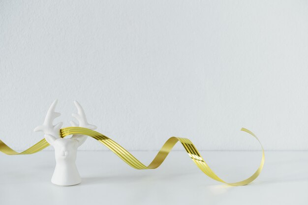 White plaster porcelain reindeer with golden ribbon . Scandinavian minimalism composition. Stylish decor concept. Copy space