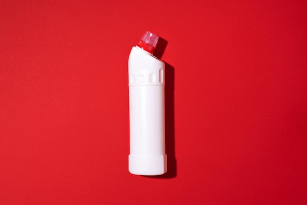 White plastic bottle of cleaning product household chemicals or liquid laundry detergent on red background Top view Flat lay Copy space Detergent bottle