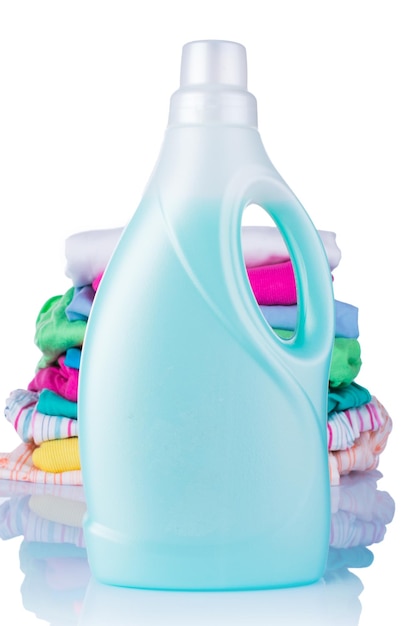 White plastic bottle of detergent and a pile of clean laundry on a white background Conditioner for linen