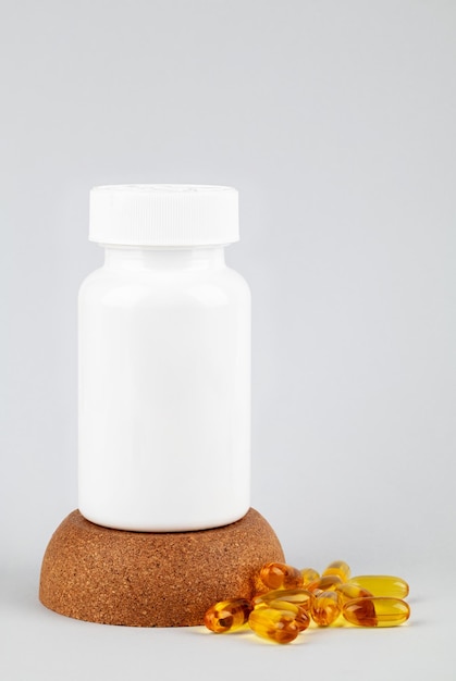 White plastic bottle with pills on a brown cork isolated on white background