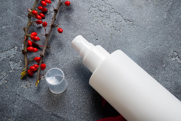 Photo white plastic bottle with spray on dark stone background with autumn decor