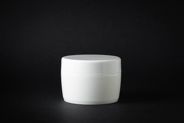 White plastic box of cream moisturizer on black background