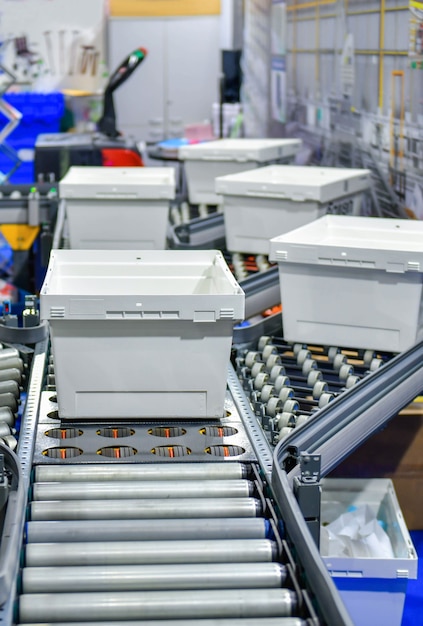 Photo white plastic boxes on conveyor belt. parcels transportation system concept