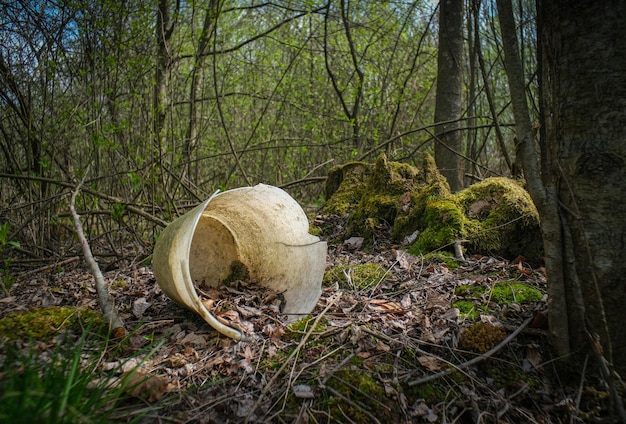 Белое пластиковое ведро лежит в лесу с порошкообразными отливками