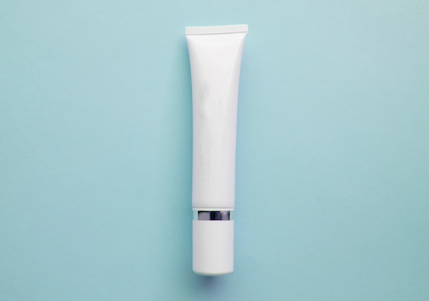 Photo white plastic cream tube with space for text on light blue background, minimalism