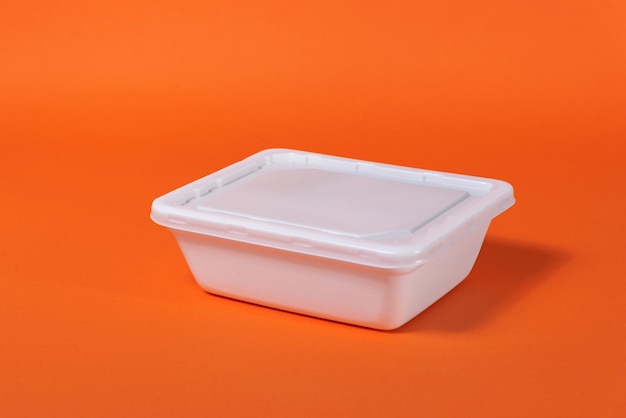 White plastic fast food box on orange background - side view, isolate