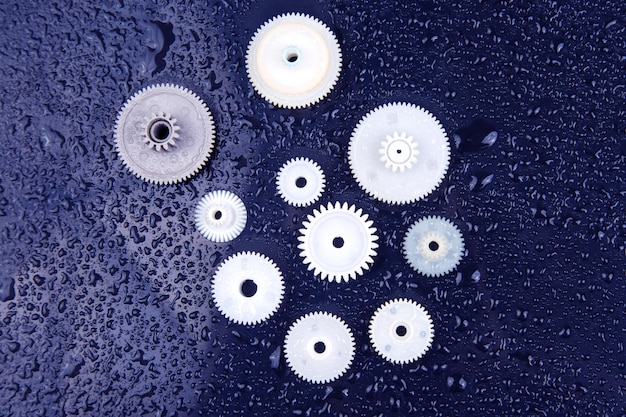 Фото Белые пластиковые шестерни на темном фоне механизма соединения детализируют предмет движения
