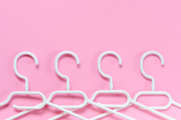 White plastic hangers on a pink background Concept for sale shop second hand online trade brand resale platform