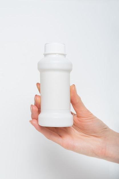 White plastic medicine bottle in a female hand.