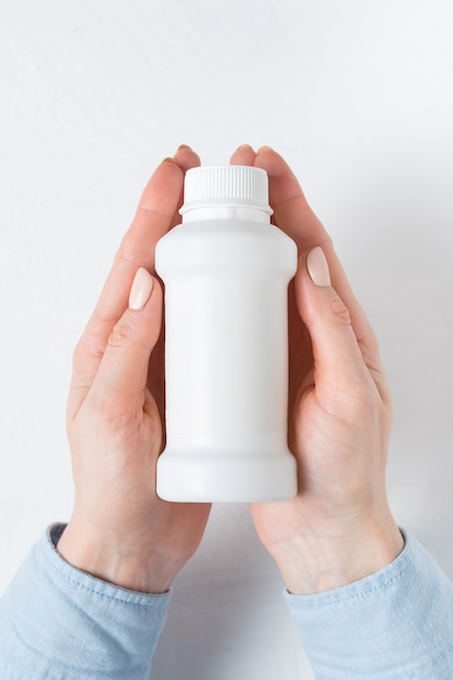 White plastic medicine bottle in a female hand, 