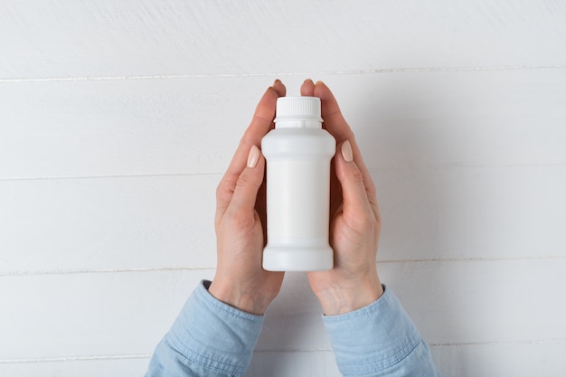 White plastic medicine bottle in a female hand. 