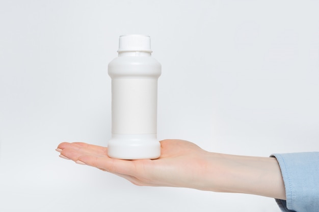 女性の手で白いプラスチック製の薬瓶、