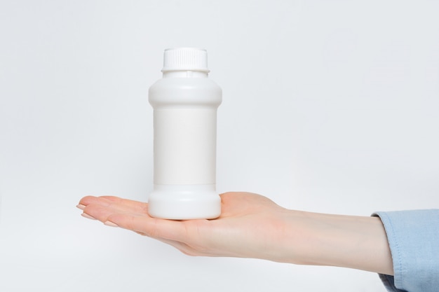 Photo white plastic medicine bottle in a female hand.