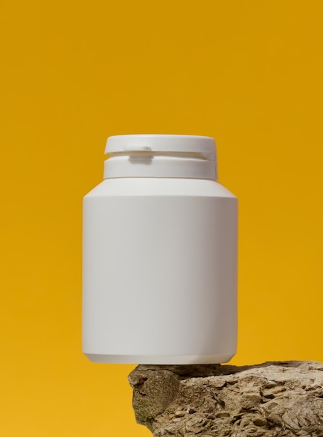 White plastic medicine jar on stone yellow background Mock up