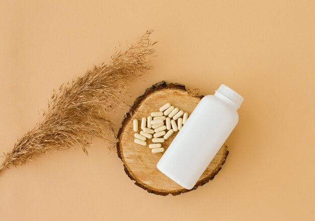 White plastic packaging on wooden podium pampas grass pills mock-up of packaging medical products