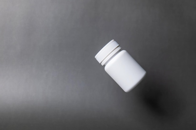 Photo white plastic pill bottle unlabelled capped floating on a black background