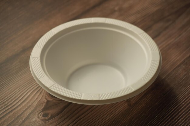Photo white plastic plate made of plastic on a wooden background