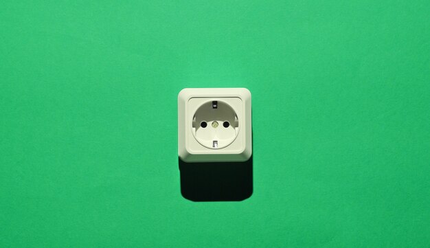 White plastic power socket on green background. Minimalism