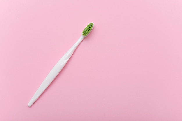 Photo white plastic toothbrush with green bristle as flat lay