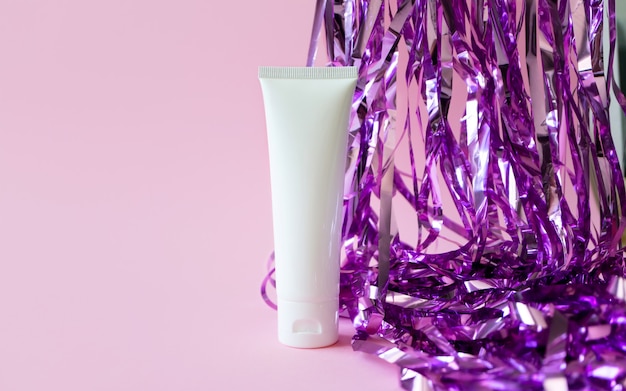 White plastic tube mockup with moisturizer cream shampoo or facial cleanser and holiday tinsel