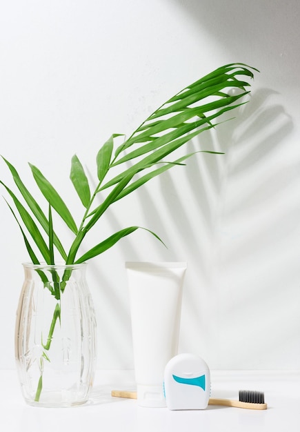 White plastic tube for toothpaste toothbrush and dental floss on white background