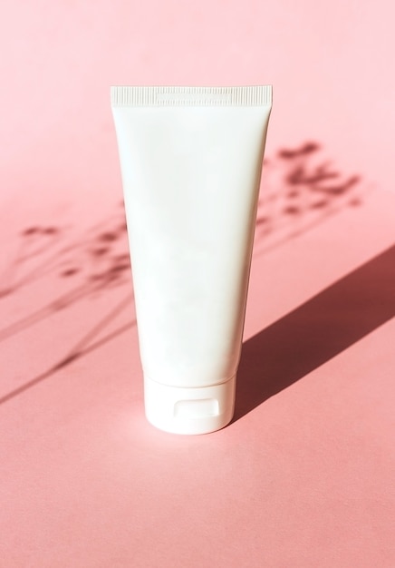 White plastic tube with face hand and body cream on pink background with shadow