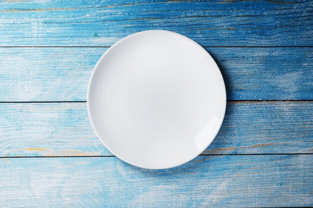 White plate on a blue background top view. Minimalistic concept