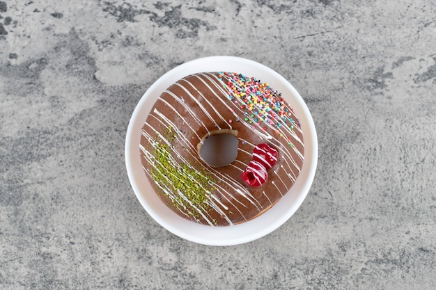 White plate of chocolate glazed donut on stone background. 