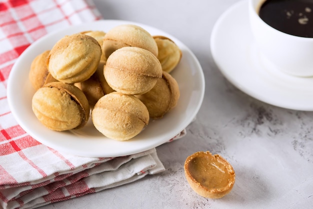 White Plate Cookies Nuts with Condensed Milk Cup of Coffee Gray Background Horizontal