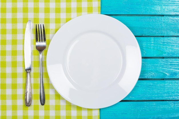 White plate and cutlery on table background