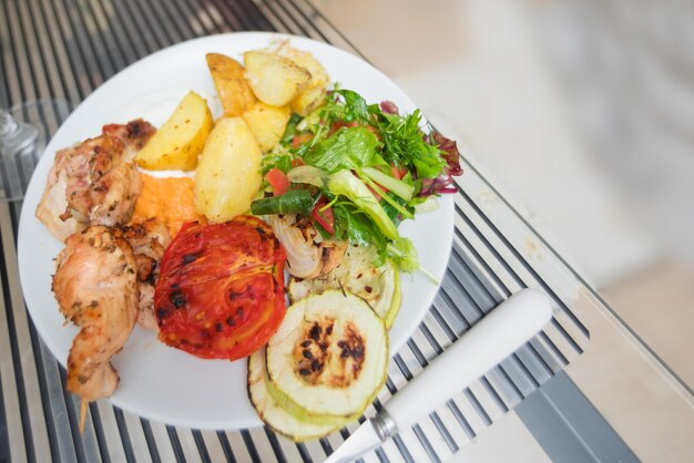 White plate on a table with fried on a grill chicken and vegetables