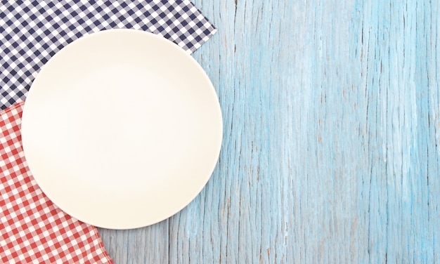 White plate on tablecloth on wood table background