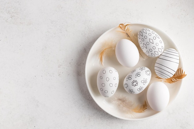 White plate with black and white decorated Easter eggs feathers