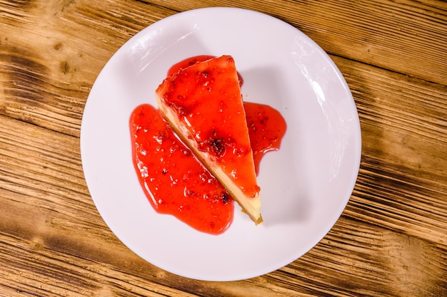 White plate with cheesecake New York and raspberry jam on wooden table Top view