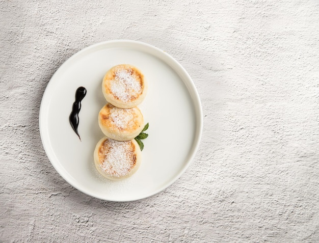 Photo a white plate with cheesecakes on a light background