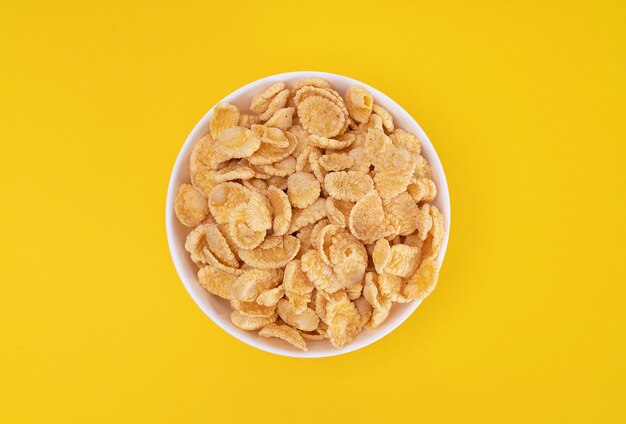 White plate with cornflakes for a delicious on yellow background