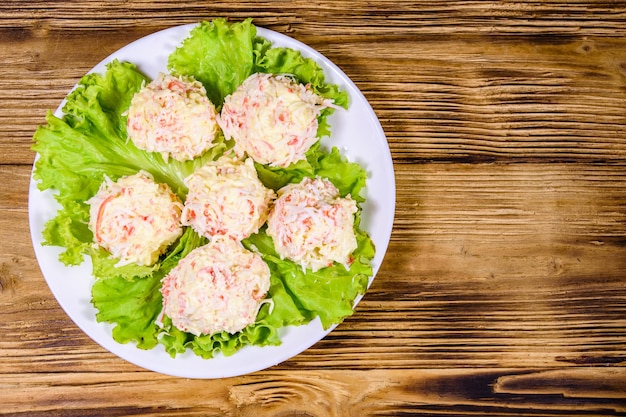 White plate with crabcheese balls and lettuce leaves on rustic wooden table Top view